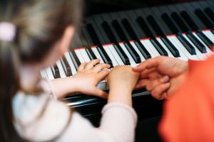 Blick über die Schulter eines Kindes, das Klavier lernt