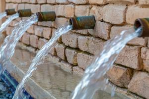 Trinkwasser tritt aus mehreren Rohren eines Brunnen aus und wird in einem Auffangbecken gesammelt.