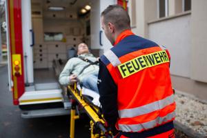 Ein Patient wird auf einer Trage durch einen Notfallsanitäter in einen Rettungswagen geschoben