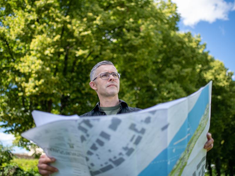 Ein Mann steht mit einer Karte in der Hand im Grünen