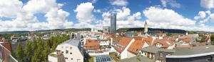 Panoramablick über Jena mit Jentower, vielen Häusern, einigen Bäumen und den Bergen im Hintergrund