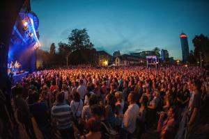 Publikum auf einem Konzert der KulturArena Jena. Im Hintergrund ist der JenTower zu sehen. 