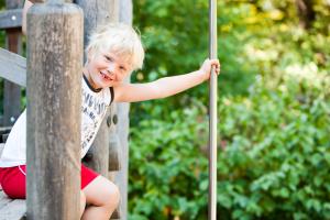 kleiner Junge auf einem Spielplatz an der Kletterstange