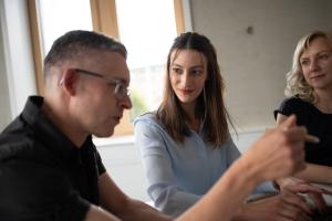 Ein Mann und zwei Frauen in einem Raum am Tisch