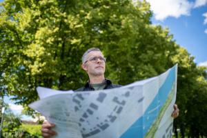 Ein Mann steht mit einer Karte in der Hand im Grünen