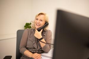 Eine Frau sitzt an einem Schreibtisch mit Monitor und telefoniert